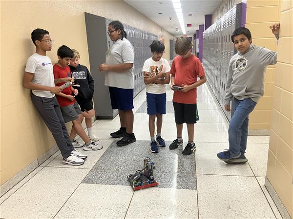 Students driving a robot in a hallway.